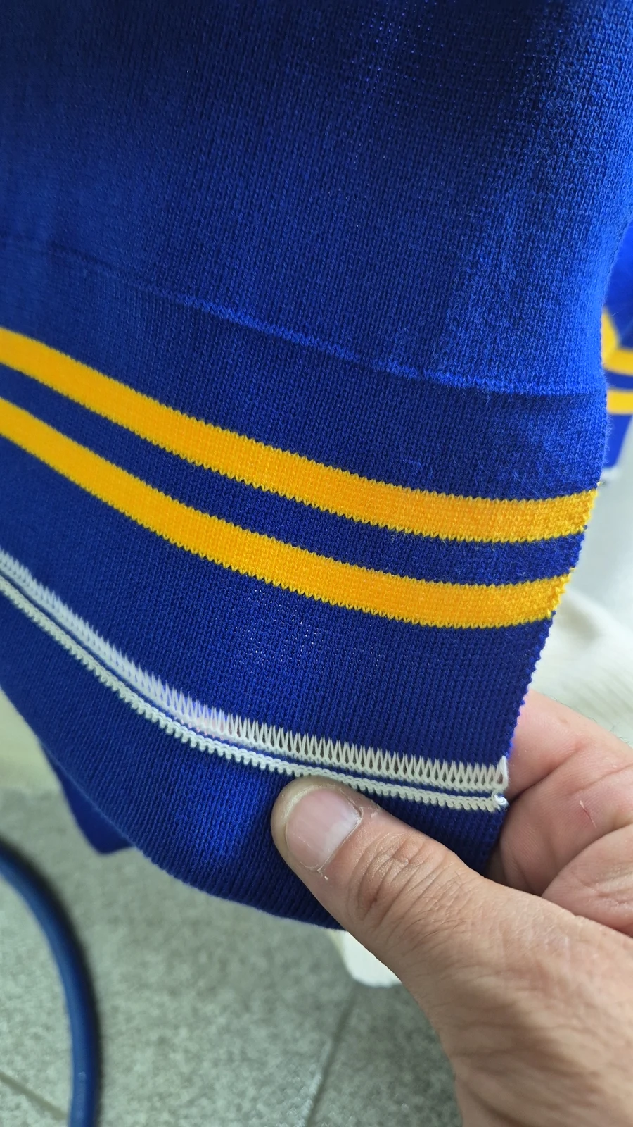 Tejido azul con franjas amarillas sostenido en el taller
